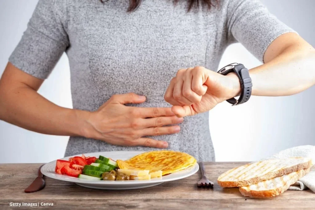 Mujer practicando ayuno intermitente revisa su reloj antes de comer.
