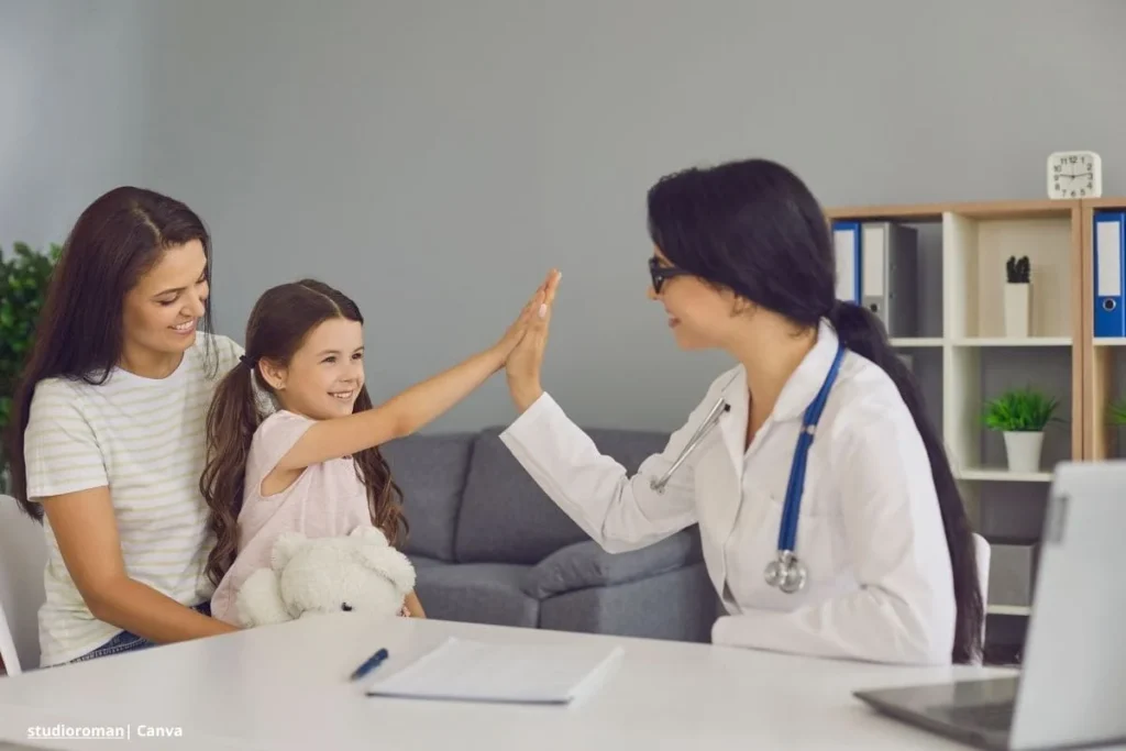 Papel de las EPS en la salud – doctora choca la palma con una niña mientras la madre observa