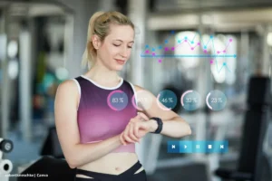 Smartwatch monitoreo de salud -Mujer en ropa deportiva mirando su smartwatch mientras datos gráficos flotan sobre la imagen, visualizando funciones de monitoreo de salud portátil y análisis de sueño mediante wearables salud Colombia.