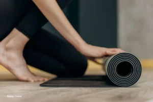 Mujer desenrollando un tapete para yoga para la longevidad en un estudio.